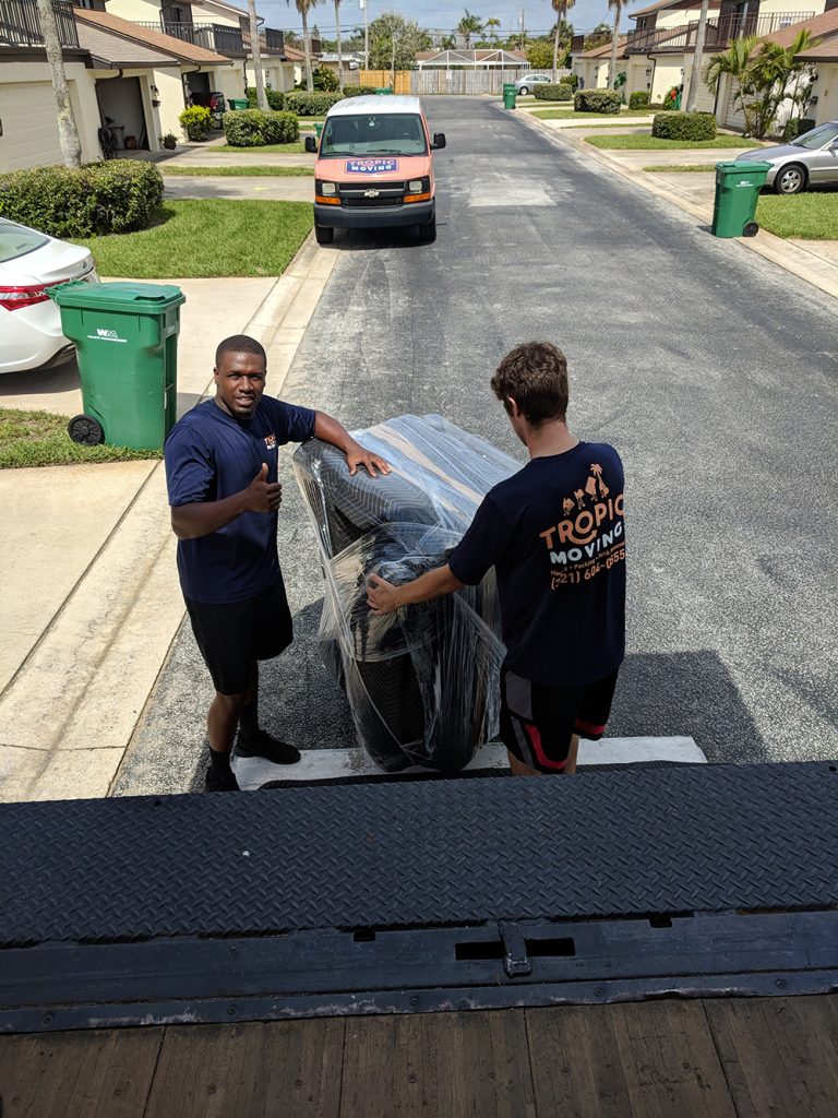 Two Tropic Moving employees putting furniture into the truck