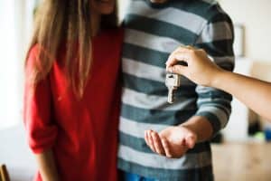 a young couple being handed the keys to an apartment