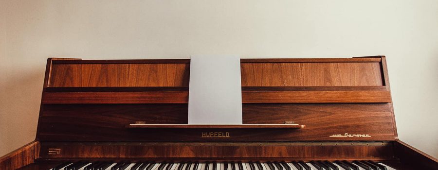 antique brown Hupfeld piano against a white wall