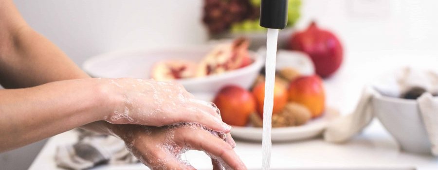 washing hands at sink with fruit behind